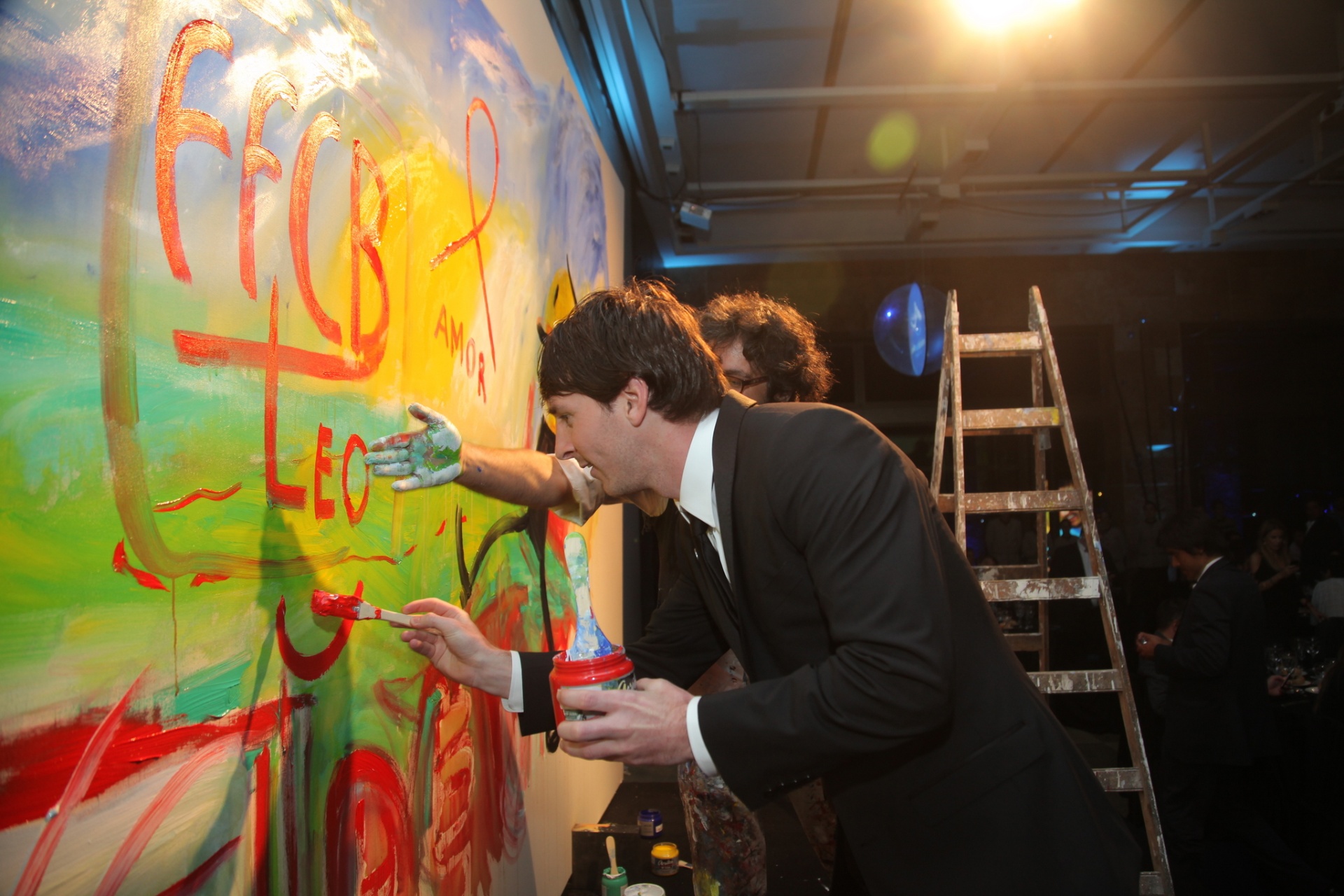 Messi adding red brushwork to the collaborative painting.